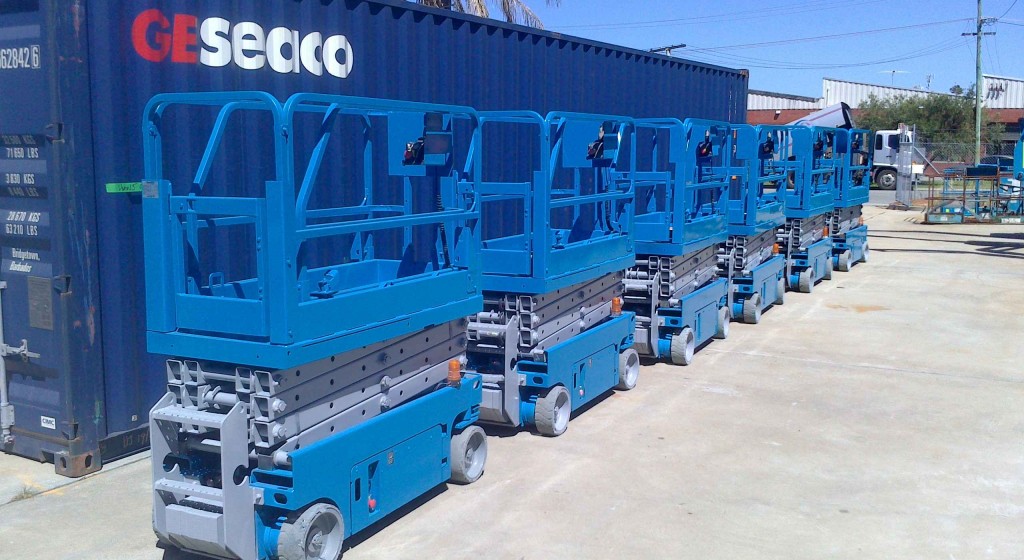 Genie scissor lifts repainted next to shipping container